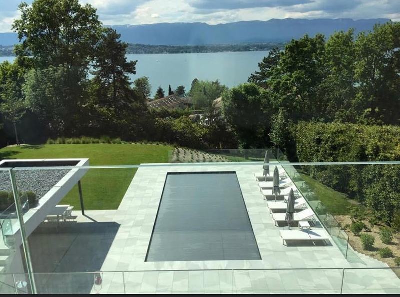 Piscine rectangulaire bordée de dalles claires, vue plongeante sur le lac